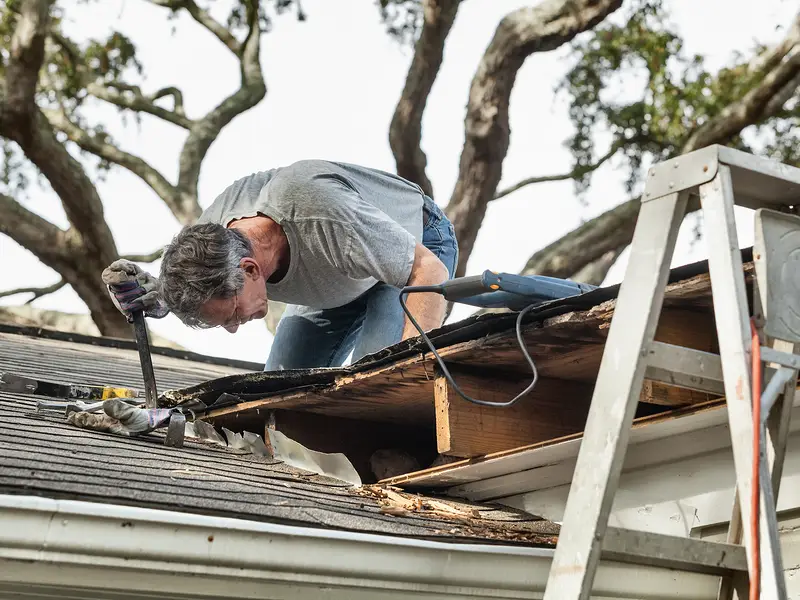 Roofer removing rotted roof boards from an older house roof